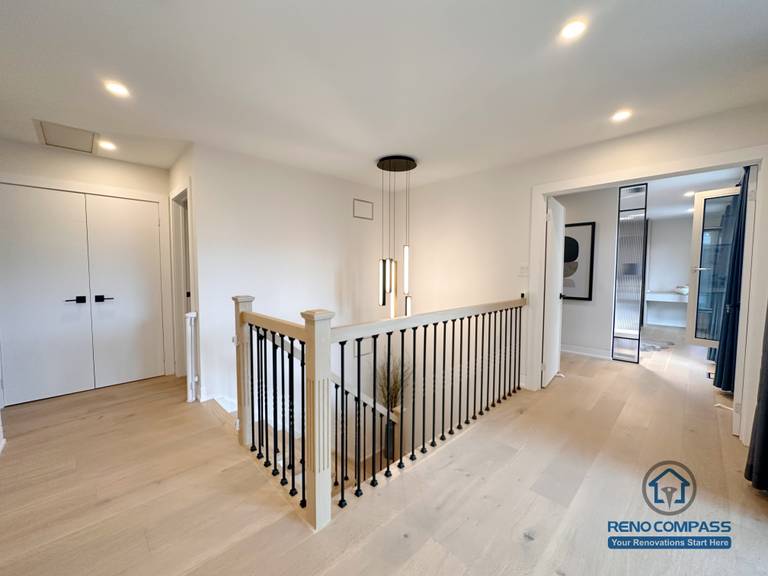 This Toronto upper-level hallway renovation features light hardwood flooring, custom stair railings, and modern pendant lighting that enhances openness and visual flow. The seamless flooring installation connects bedrooms and common areas, showcasing refined craftsmanship ideal for contemporary Toronto home renovations.
