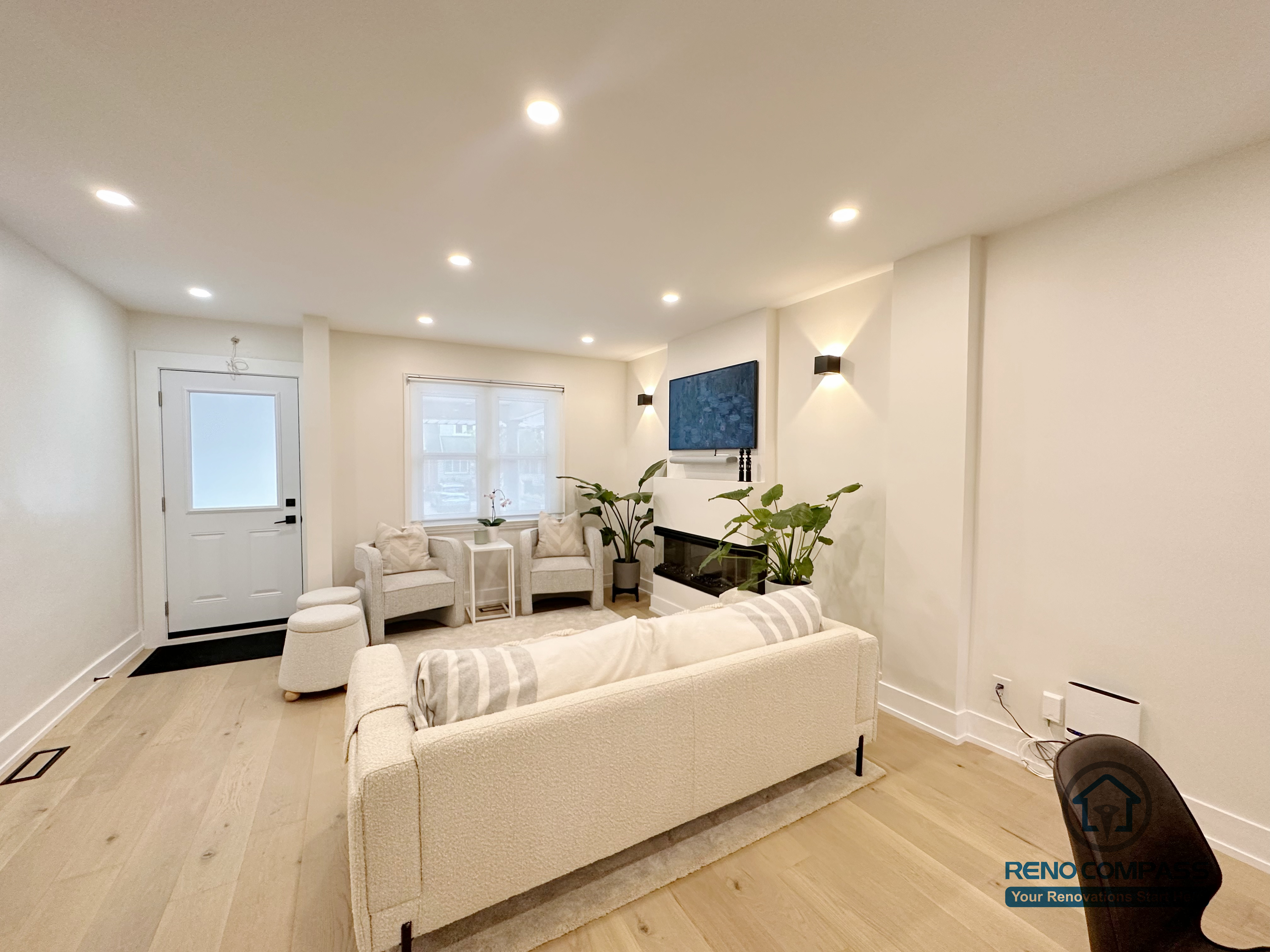This Toronto interior renovation features a bright modern living room with a built-in linear fireplace, recessed ceiling lighting, wide-plank hardwood flooring, and an open layout connecting the dining and kitchen areas. The balanced design creates a warm yet contemporary living space, completed by a professional Toronto renovation company.