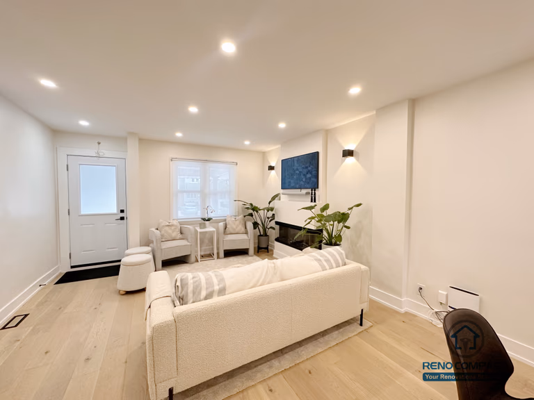 This Toronto interior renovation features a bright modern living room with a built-in linear fireplace, recessed ceiling lighting, wide-plank hardwood flooring, and an open layout connecting the dining and kitchen areas. The balanced design creates a warm yet contemporary living space, completed by a professional Toronto renovation company.