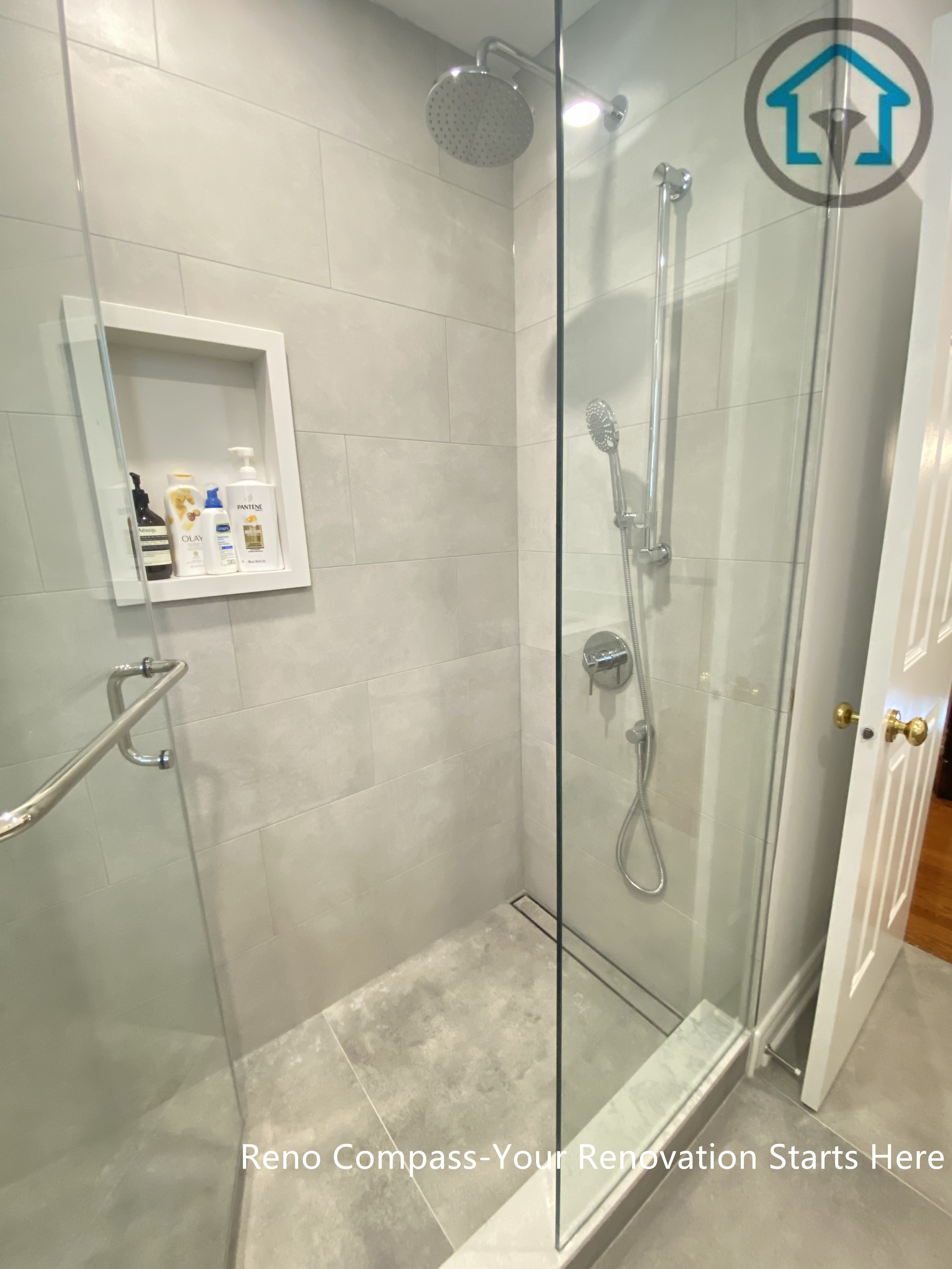 This image highlights the walk-in shower design in an Oakville bathroom renovation, featuring a frameless glass enclosure and large-format grey wall tiles. A recessed shower niche provides practical storage while keeping the overall look clean and uncluttered. The simple tile palette and clear glass panels enhance the sense of space and make daily maintenance easier, creating a shower area that is both modern and functional.