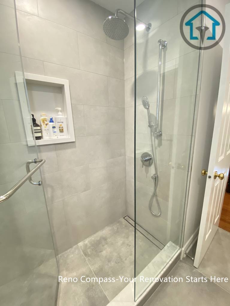 This image highlights the walk-in shower design in an Oakville bathroom renovation, featuring a frameless glass enclosure and large-format grey wall tiles. A recessed shower niche provides practical storage while keeping the overall look clean and uncluttered. The simple tile palette and clear glass panels enhance the sense of space and make daily maintenance easier, creating a shower area that is both modern and functional.