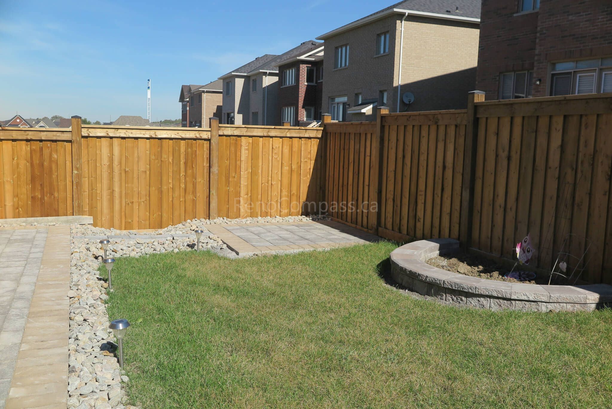 Custom curved garden bed and retaining wall completed in this Aurora backyard landscaping project. The stone border design creates a clean planting area against the wooden fence while maintaining a modern and low-maintenance outdoor layout. Professionally installed by Reno Compass Inc., a trusted Toronto landscaping and renovation contractor serving Aurora and the GTA.