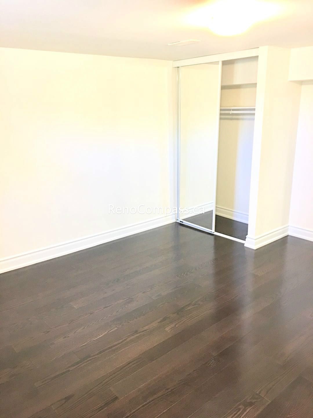 This Toronto basement renovation features a newly finished bedroom with rich hardwood flooring, fresh neutral walls, and a built-in closet with sliding doors. The clean layout and warm lighting create a comfortable and functional living space ideal for rental or family use. Completed by a professional Toronto renovation company, this basement bedroom upgrade enhances both property value and everyday living comfort.