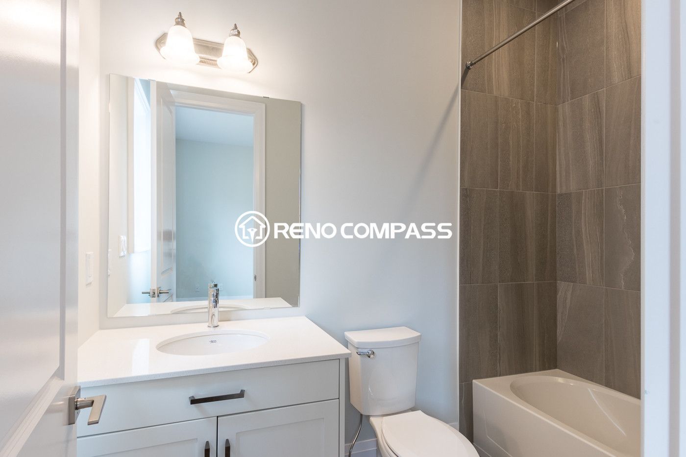 Clean and modern bathroom renovation in Newmarket featuring a vanity cabinet with quartz countertop, bathtub and shower combination, and contemporary wall tile design. Completed by a professional Toronto renovation company, this bathroom upgrade improves both comfort and functionality for daily living.