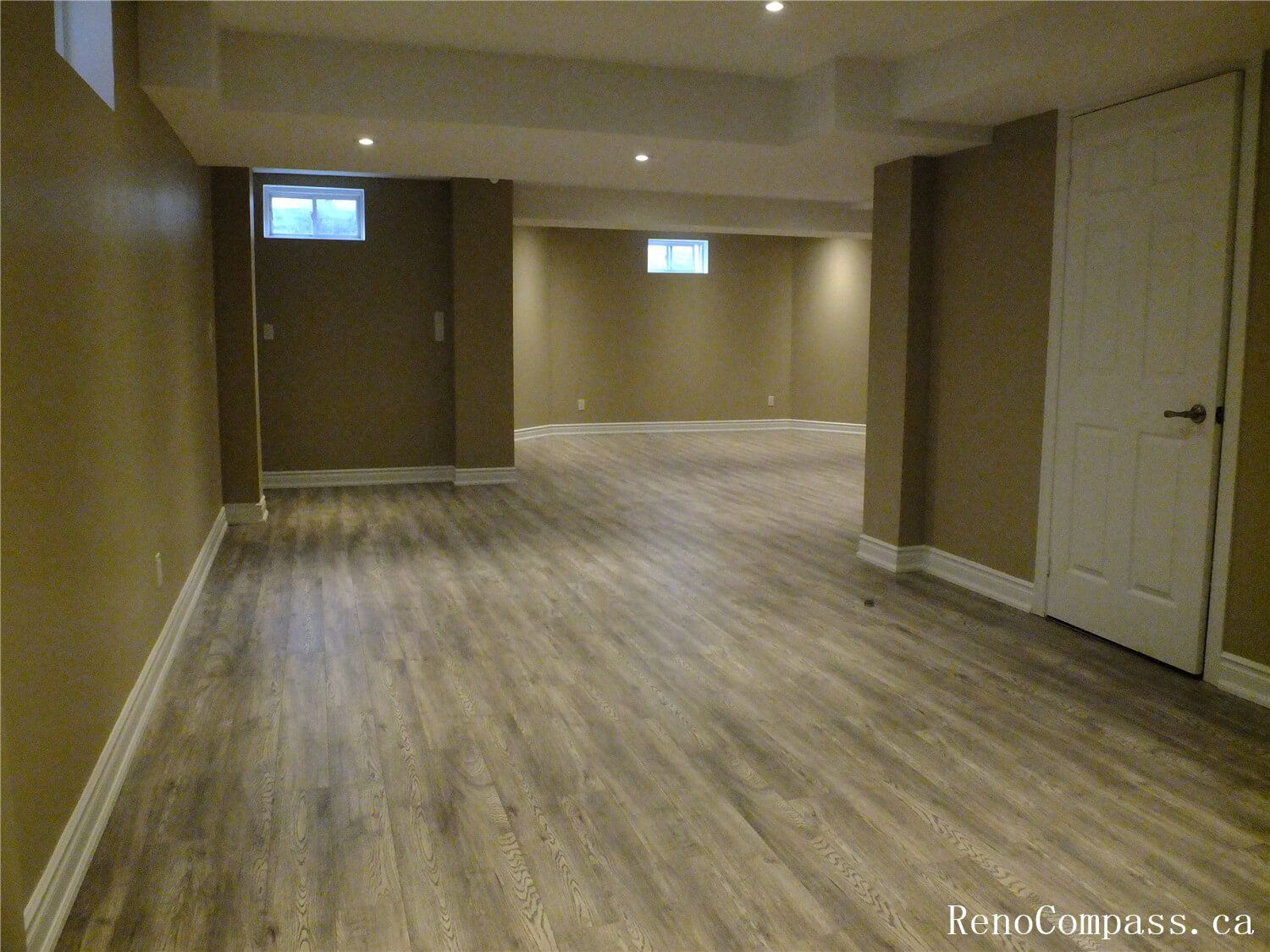 Transform your home with a professional basement renovation in Ajax. This open-concept recreation room features high-quality vinyl flooring, recessed pot lighting, and a modern neutral color palette—ideal for a family living space or home gym.