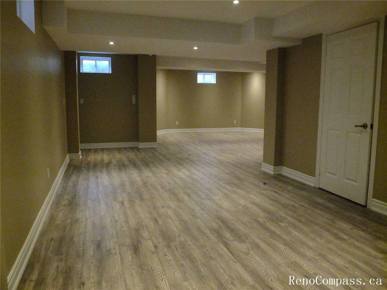 Transform your home with a professional basement renovation in Ajax. This open-concept recreation room features high-quality vinyl flooring, recessed pot lighting, and a modern neutral color palette—ideal for a family living space or home gym.