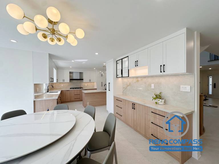 A modern dining room featuring a custom built-in buffet cabinet, quartz countertop, glass display cabinets, integrated storage, and an open-concept layout connecting the kitchen and dining area. Completed during a luxury whole home renovation in Markham, Ontario, this contemporary space combines elegant millwork, practical functionality, and premium craftsmanship by Reno Compass.