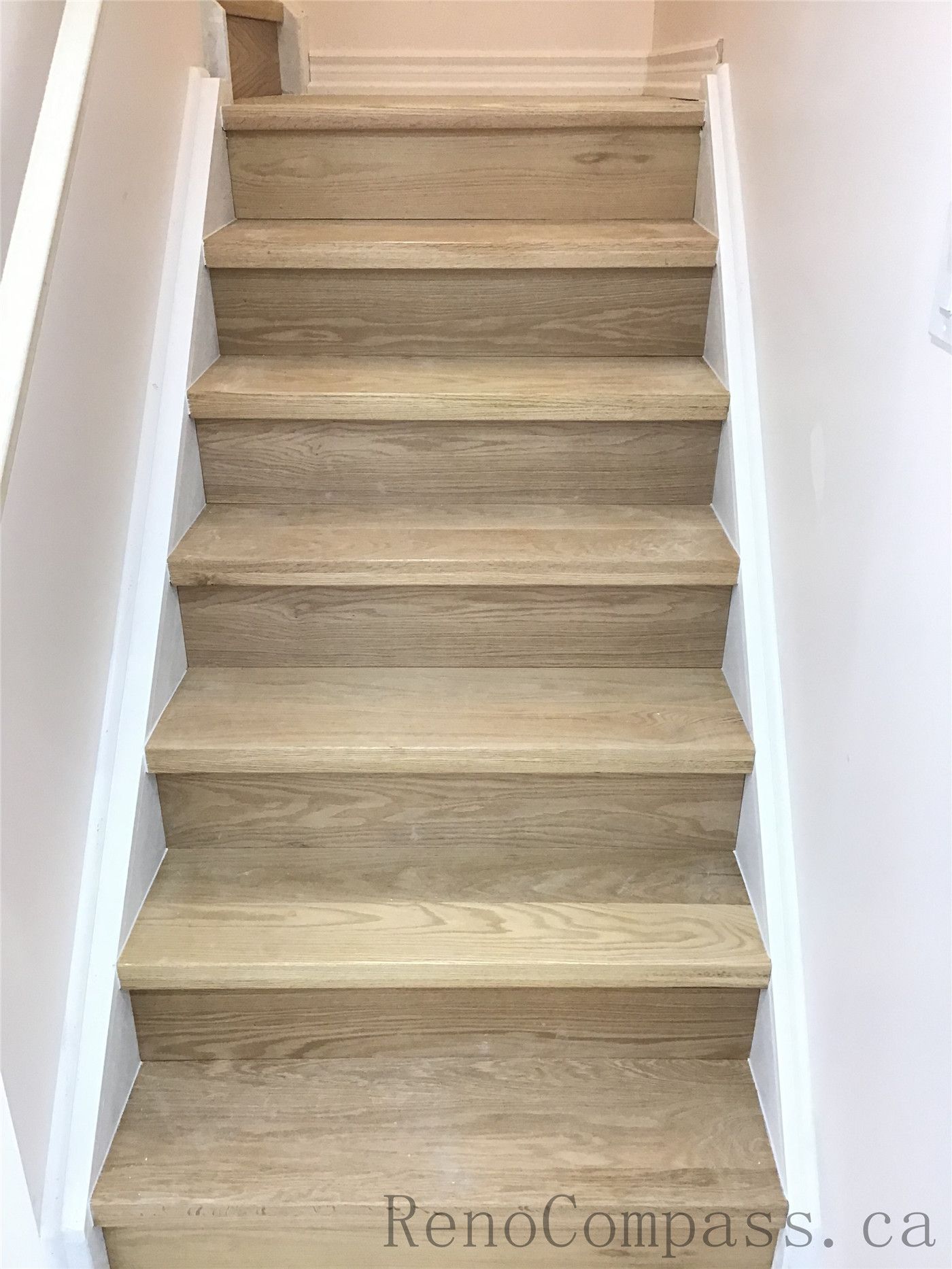 Newly installed modern wooden staircase for this Pickering basement renovation project, featuring natural-tone wood steps, clean white side walls, and a bright contemporary finish. The upgraded basement stairs improve both safety and visual flow, creating a seamless transition to the newly finished lower level. Completed by Reno Compass Inc., a professional Toronto Renovation Company.