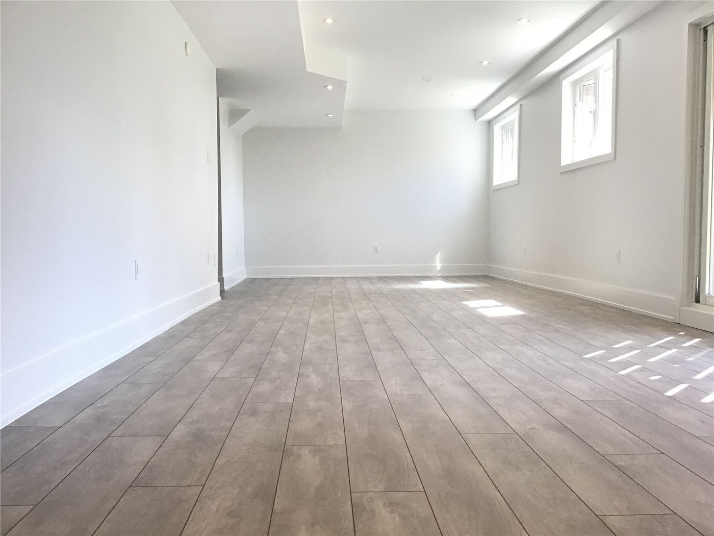 This Markham full home renovation features a spacious and fully finished basement with modern vinyl plank flooring, recessed lighting, and large windows for natural light. The open layout provides flexible space for entertainment, home office, or additional living areas. Completed by a trusted Toronto Renovation Company, this basement design enhances both usability and property value.