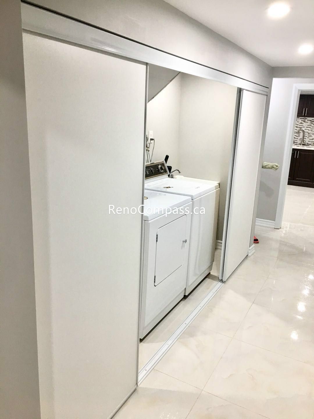 This Toronto basement renovation includes a clean and functional laundry area with modern sliding closet doors for a streamlined and organized look. The concealed washer and dryer setup maximizes space while maintaining a tidy and contemporary basement design. Completed by Reno Compass Inc., this basement upgrade enhances practicality, storage efficiency, and overall home value with quality workmanship and thoughtful layout planning.