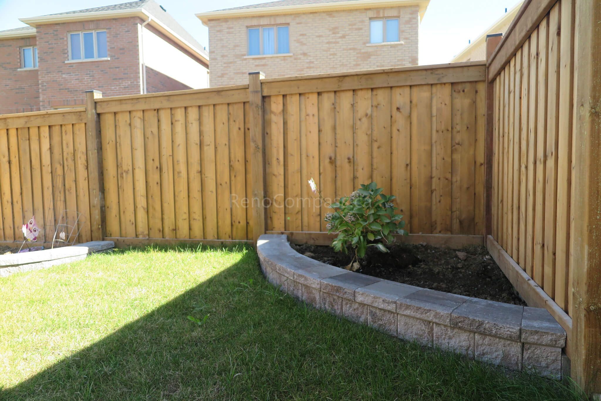 Custom curved garden bed and retaining wall completed in this Aurora backyard landscaping project. The stone border design creates a clean planting area against the wooden fence while maintaining a modern and low-maintenance outdoor layout. Professionally installed by Reno Compass Inc., a trusted Toronto landscaping and renovation contractor serving Aurora and the GTA.