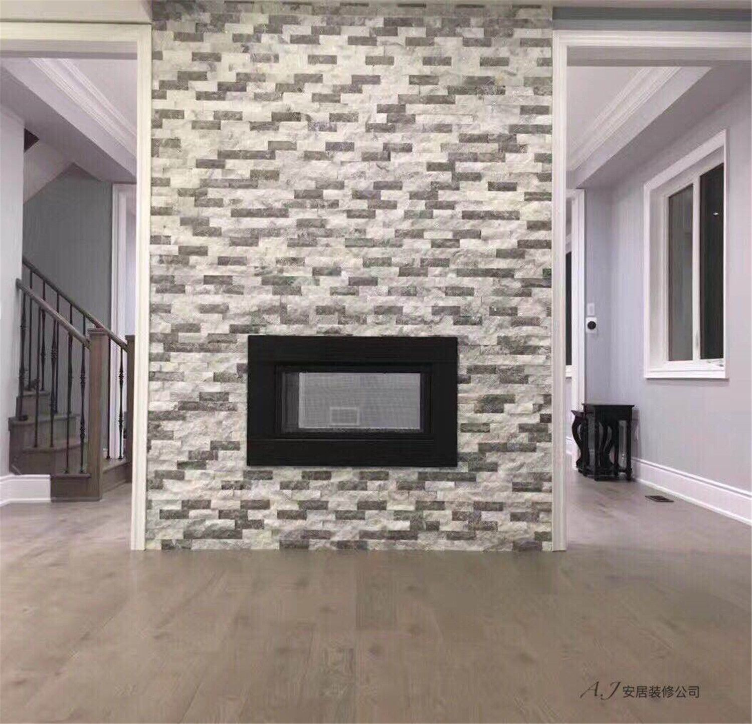 This Scarborough interior renovation highlights a striking stone fireplace feature wall that serves as the focal point of the living space. The textured stacked-stone design adds depth and character, complemented by warm wood flooring, clean white trim, and soft grey wall tones. The balanced layout connects the staircase and adjacent rooms while maintaining an open and elegant atmosphere, showcasing a modern and refined interior renovation in Scarborough.