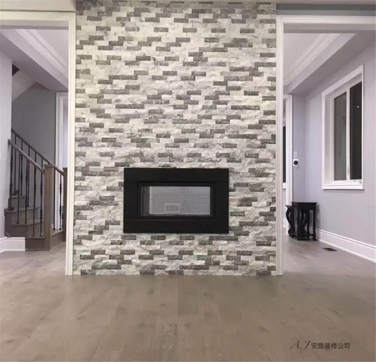 This Scarborough interior renovation highlights a striking stone fireplace feature wall that serves as the focal point of the living space. The textured stacked-stone design adds depth and character, complemented by warm wood flooring, clean white trim, and soft grey wall tones. The balanced layout connects the staircase and adjacent rooms while maintaining an open and elegant atmosphere, showcasing a modern and refined interior renovation in Scarborough.