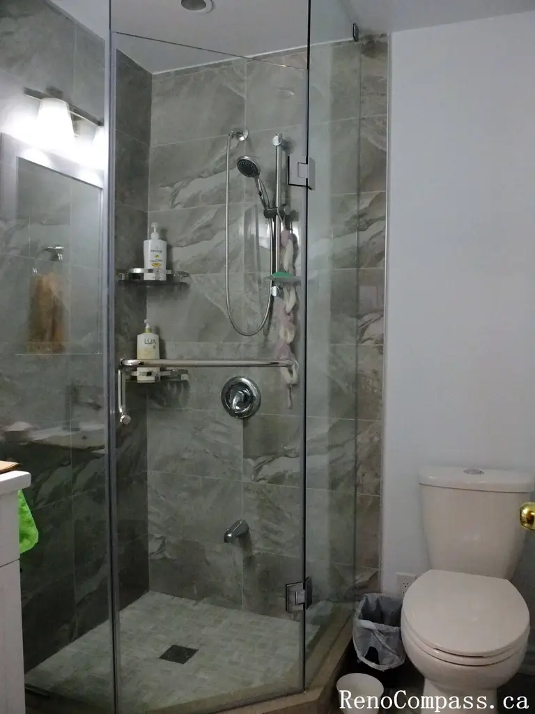 Bathroom interior renovation in North York featuring a frameless glass shower, marble-look porcelain tiles, built-in shower shelf, and modern chrome fixtures. This Toronto interior renovation emphasizes clean lines, functional storage, and durable materials for everyday residential use.