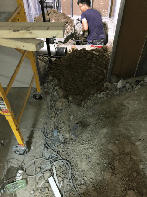 This image shows the early construction phase of a commercial retail store renovation, including floor excavation and underground plumbing preparation. The renovation team is performing structural groundwork to support new drainage, utility lines, and flooring installation for the upgraded retail space. Reno Compass Inc. ensures all foundational and infrastructure work is completed with precision to support a safe, durable, and high-quality commercial renovation.