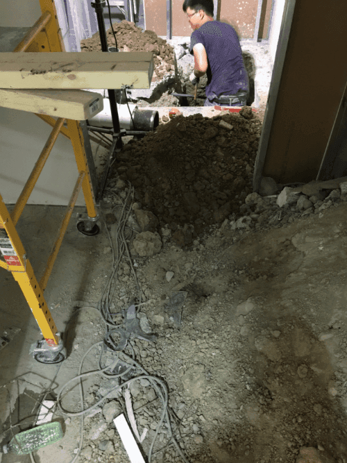 This image shows the early construction phase of a commercial retail store renovation, including floor excavation and underground plumbing preparation. The renovation team is performing structural groundwork to support new drainage, utility lines, and flooring installation for the upgraded retail space. Reno Compass Inc. ensures all foundational and infrastructure work is completed with precision to support a safe, durable, and high-quality commercial renovation.