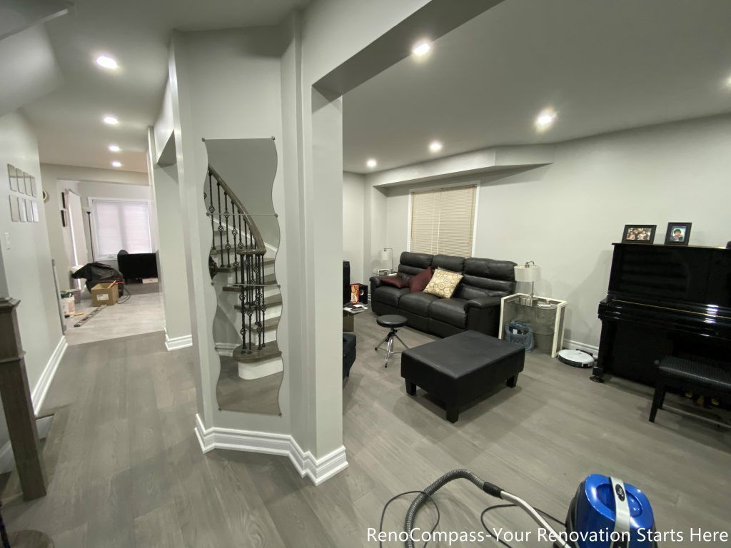 This Mississauga interior renovation features a modern open-concept living space with upgraded flooring, smooth ceilings, and recessed pot lights that create a bright and welcoming atmosphere. The redesigned layout highlights a custom staircase feature wall, contemporary trim work, and a seamless transition between living and dining areas. Completed by a professional Toronto renovation company, this renovation focuses on enhancing space flow, lighting quality, and overall home comfort while adding long-term value and a clean modern aesthetic.