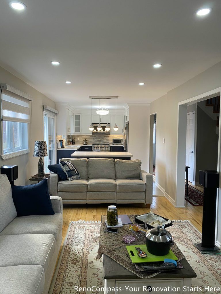 A bright open-concept living area completed as part of a Newmarket interior renovation, featuring neutral tones, recessed lighting, hardwood flooring, and a seamless connection between the living, dining, and kitchen spaces by a Toronto renovation company.