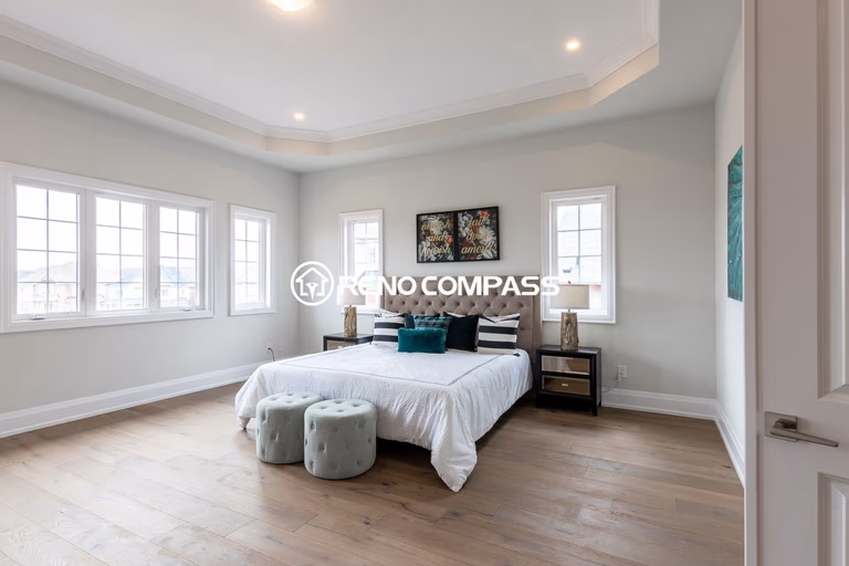 This image shows a master bedroom flooring renovation in a Newmarket home, featuring professionally installed engineered wood flooring. The natural wood flooring enhances the brightness and comfort of the space while providing durability and stability. The project was completed by Reno Compass Inc., a Toronto renovation company specializing in flooring and interior renovations.