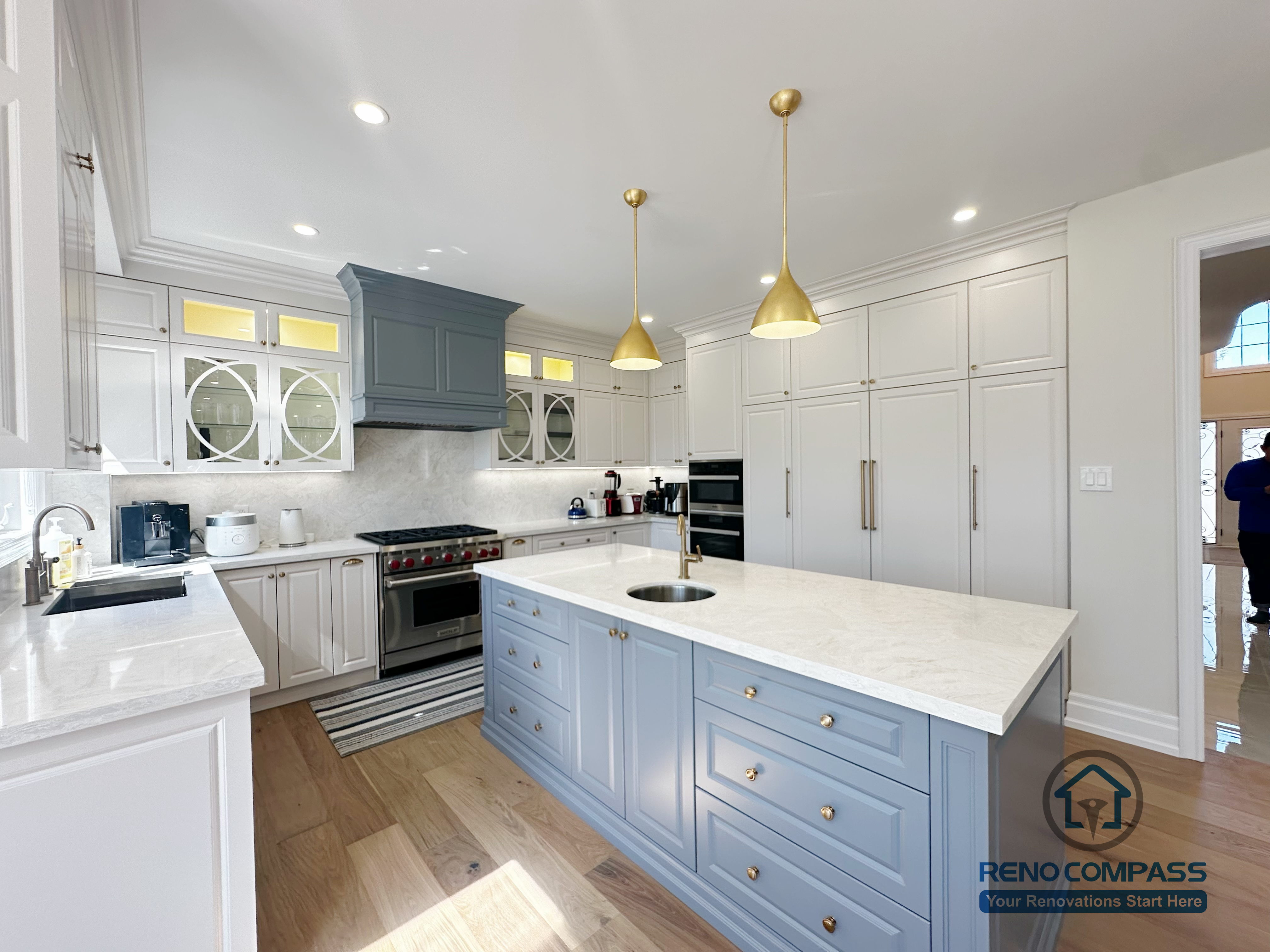 This North York kitchen renovation highlights a custom blue island with integrated drawers, full-height built-in cabinetry, and balanced recessed and pendant lighting. The layout maximizes storage efficiency while maintaining clean lines and visual symmetry, creating a refined and highly functional kitchen space designed and built by Reno Compass.