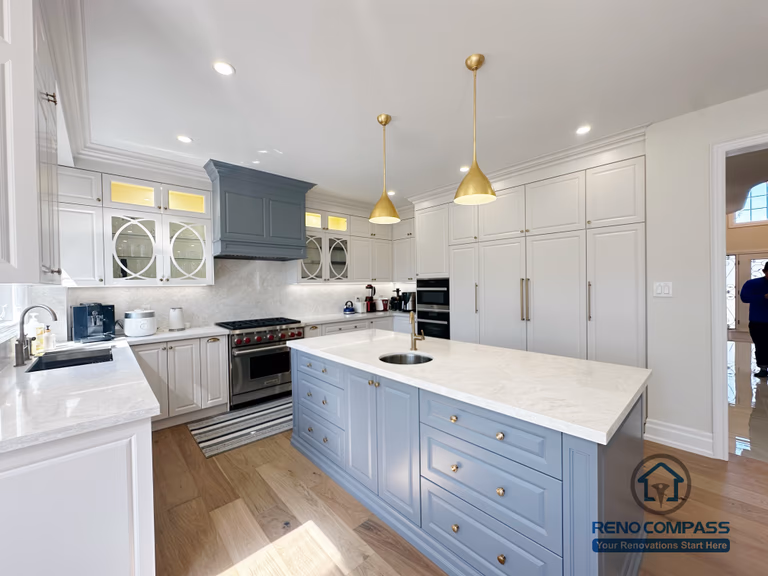 This North York kitchen renovation highlights a custom blue island with integrated drawers, full-height built-in cabinetry, and balanced recessed and pendant lighting. The layout maximizes storage efficiency while maintaining clean lines and visual symmetry, creating a refined and highly functional kitchen space designed and built by Reno Compass.