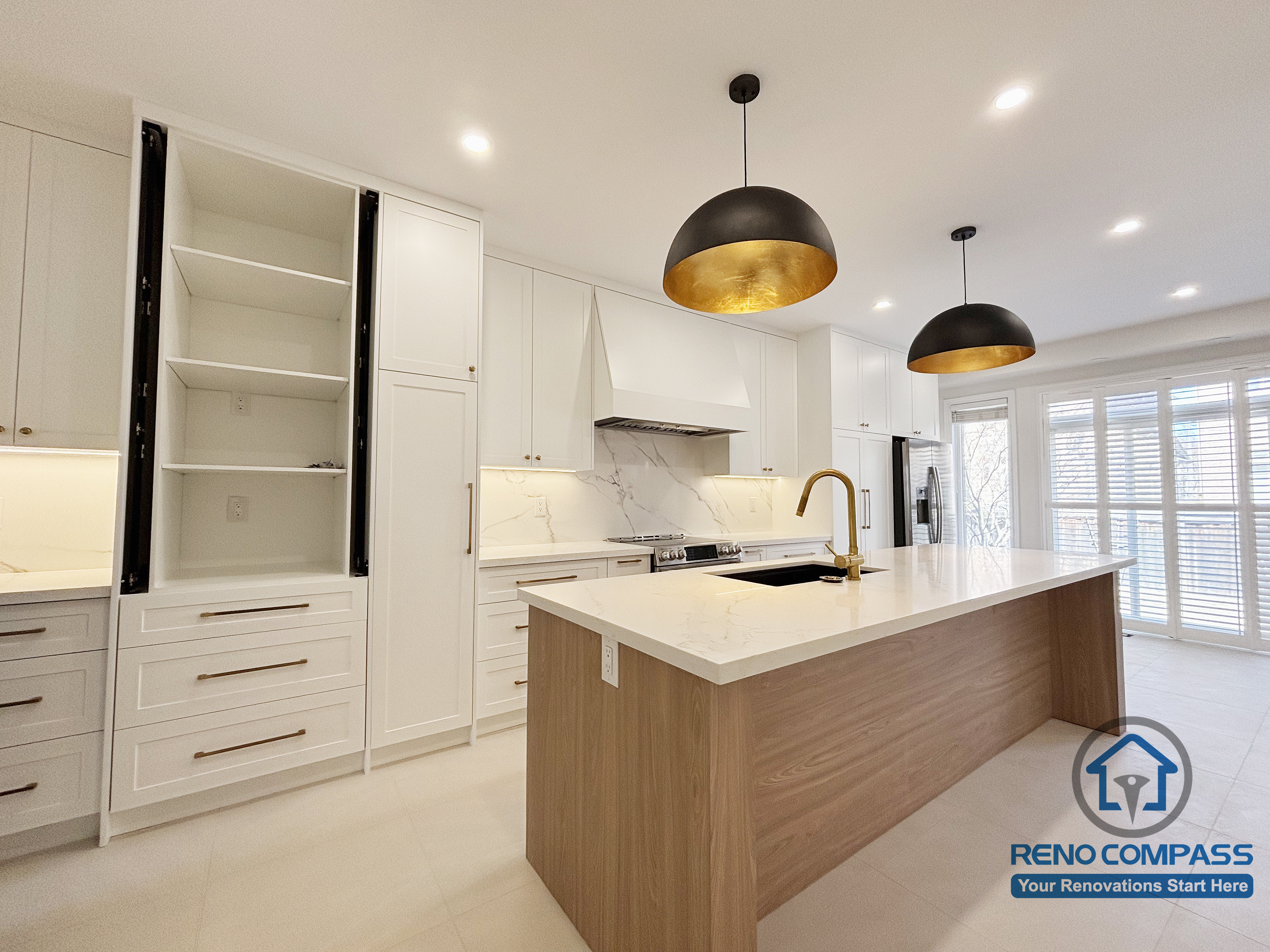 This Oakville kitchen renovation highlights a large central island paired with full-height cabinetry and integrated storage solutions. The layout supports efficient cooking workflows while maintaining a clean and uncluttered appearance. Warm wood finishes on the island contrast with crisp white cabinetry, and pendant lighting adds focused illumination over the workspace. Completed by Reno Compass, this kitchen design balances functionality, storage capacity, and long-term usability for a modern Oakville home.