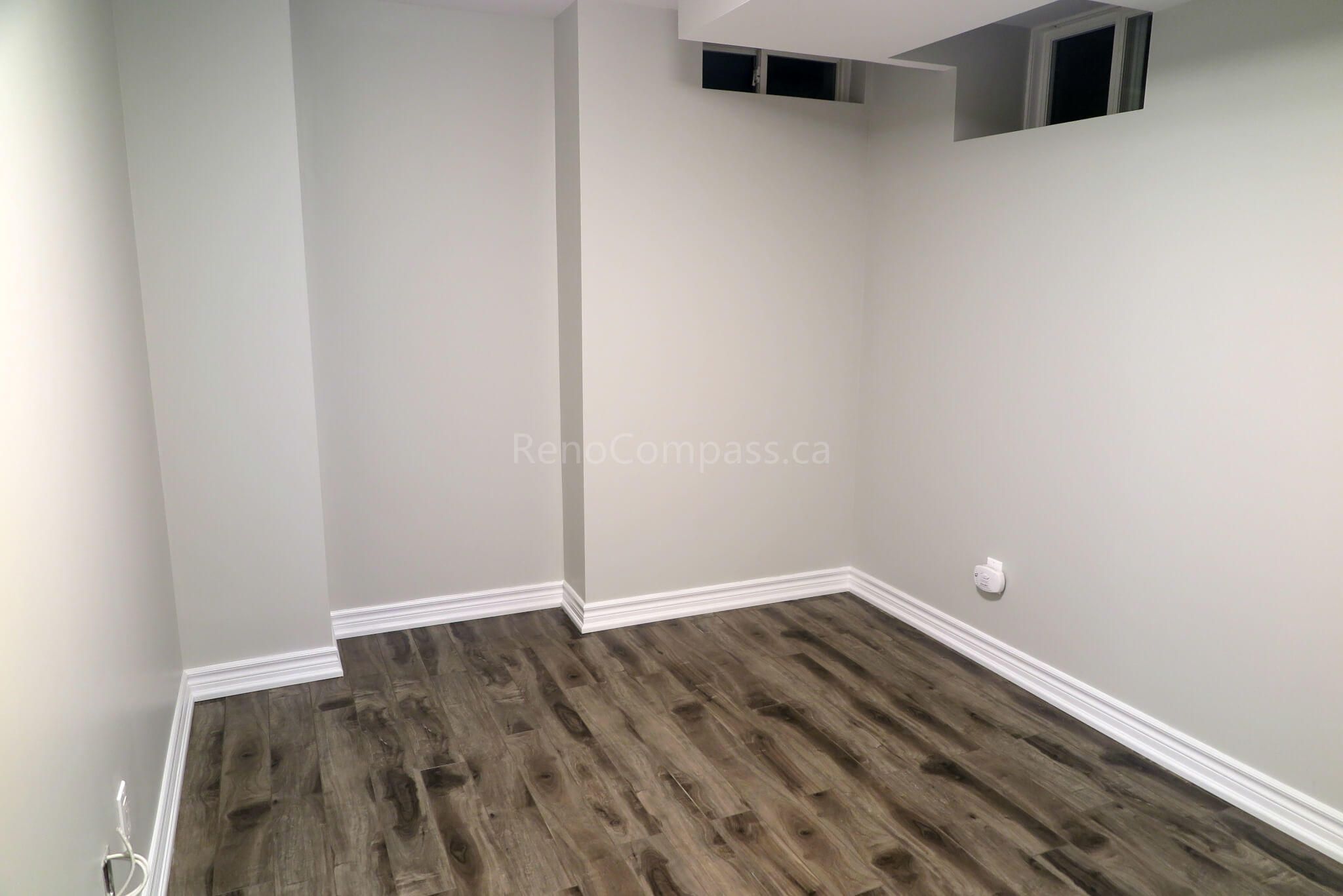Completed basement renovation in Richmond Hill featuring freshly painted walls and new wood-look flooring, ready for furniture and décor.