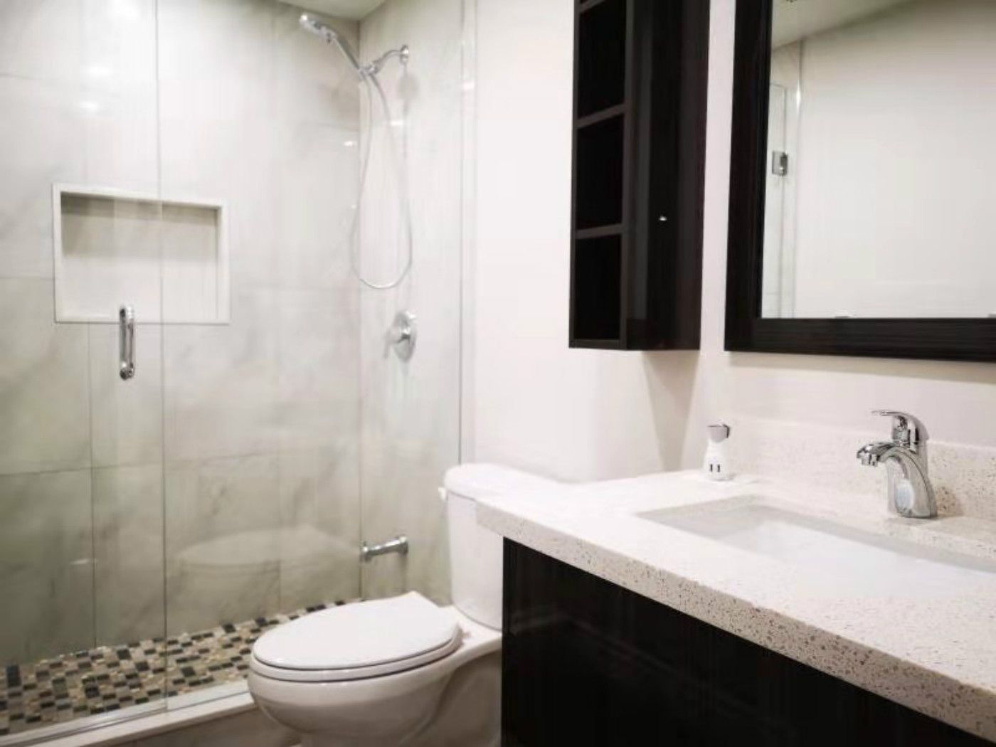 This finished Mississauga basement bathroom features a sleek glass-enclosed shower with built-in niche, modern vanity with quartz countertop, and updated fixtures. The clean tile design and efficient layout reflect the quality craftsmanship of a professional Toronto renovation company, delivering both style and functionality in a compact space.