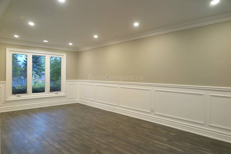 This Markham interior renovation showcases a bright and elegant living space featuring custom wall panel molding, crown molding details, and newly installed dark hardwood flooring. Recessed LED pot lights provide balanced lighting throughout the room, while large windows enhance natural light and openness. Completed by Reno Compass, a professional renovation contractor specializing in high-quality interior renovations and custom finishing services across Markham and the Greater Toronto Area.