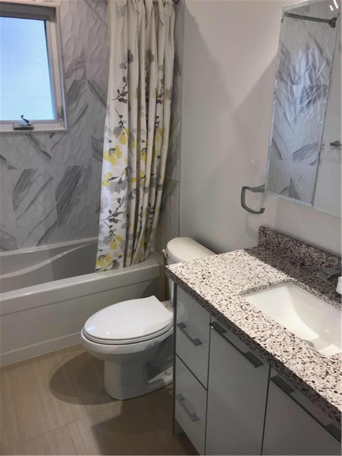 This North York bathroom renovation features a practical bathroom layout with a bathtub, quartz vanity countertop, and a window that provides natural light. Durable finishes, neutral tones, and efficient space planning create a comfortable and easy-to-maintain bathroom ideal for everyday family use.