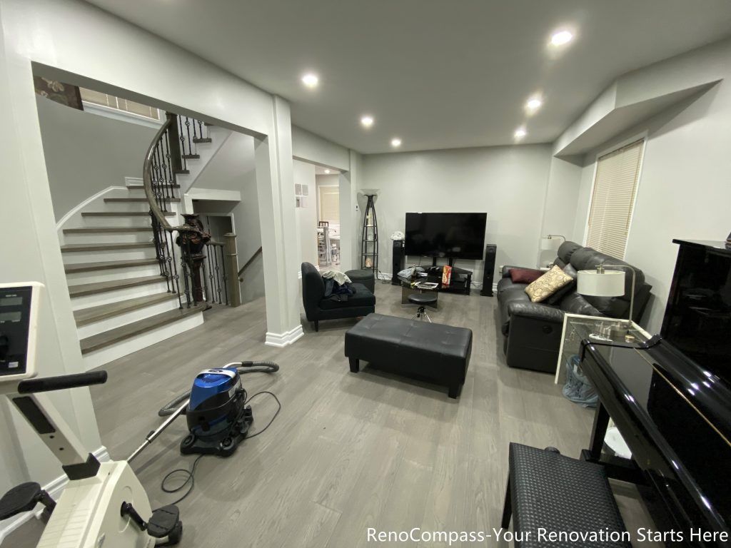 This Mississauga interior renovation features a modern open-concept living space with upgraded flooring, smooth ceilings, and recessed pot lights that create a bright and welcoming atmosphere. The redesigned layout highlights a custom staircase feature wall, contemporary trim work, and a seamless transition between living and dining areas. Completed by a professional Toronto renovation company, this renovation focuses on enhancing space flow, lighting quality, and overall home comfort while adding long-term value and a clean modern aesthetic.