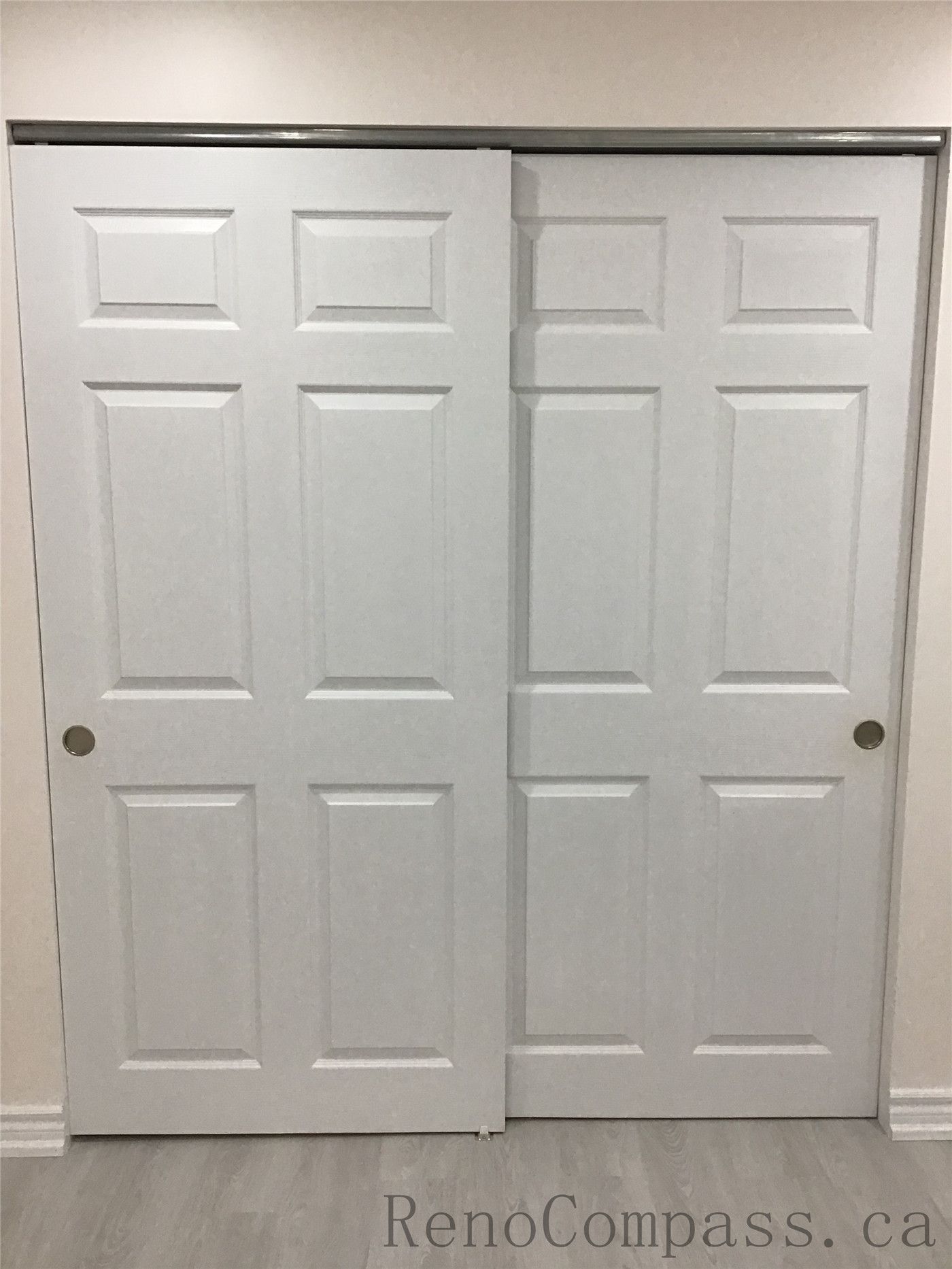 Newly installed white sliding closet doors in this Pickering basement renovation project, featuring a clean modern panel design that maximizes storage while saving space. The upgraded basement storage area complements the new flooring and bright interior finishes, creating a functional and organized living space. Completed by Reno Compass Inc., a reliable Toronto Renovation Company.