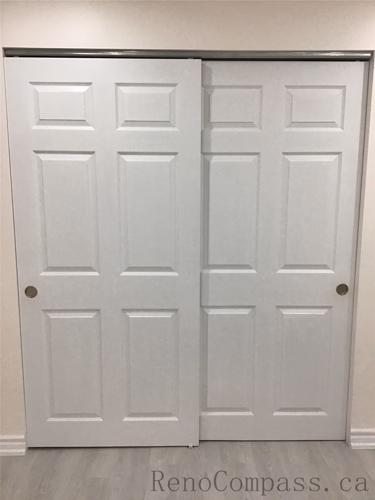 Newly installed white sliding closet doors in this Pickering basement renovation project, featuring a clean modern panel design that maximizes storage while saving space. The upgraded basement storage area complements the new flooring and bright interior finishes, creating a functional and organized living space. Completed by Reno Compass Inc., a reliable Toronto Renovation Company.