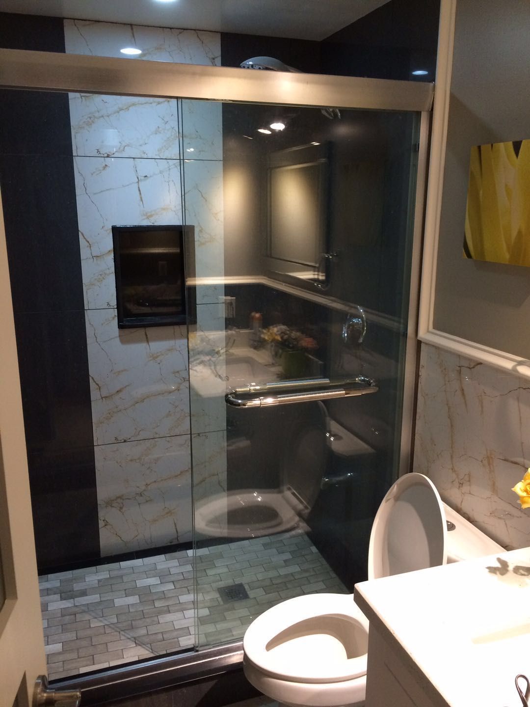 This Toronto bathroom renovation project features a modern glass shower enclosure and upgraded interior finishes designed to improve both functionality and visual appeal. The frameless glass shower creates an open, spacious feel while allowing natural and artificial light to flow throughout the bathroom.

Marble-look wall tiles paired with textured floor tiles add contrast and durability, creating a sleek and contemporary shower space. The layout maximizes efficiency within a compact footprint, integrating essential fixtures such as the vanity and toilet while maintaining comfort and accessibility.

Completed by a professional Toronto renovation company, this bathroom upgrade highlights quality tile installation, precise glass fitting, and thoughtful space planning. The finished result delivers a clean, modern bathroom that enhances daily comfort and long-term home value.