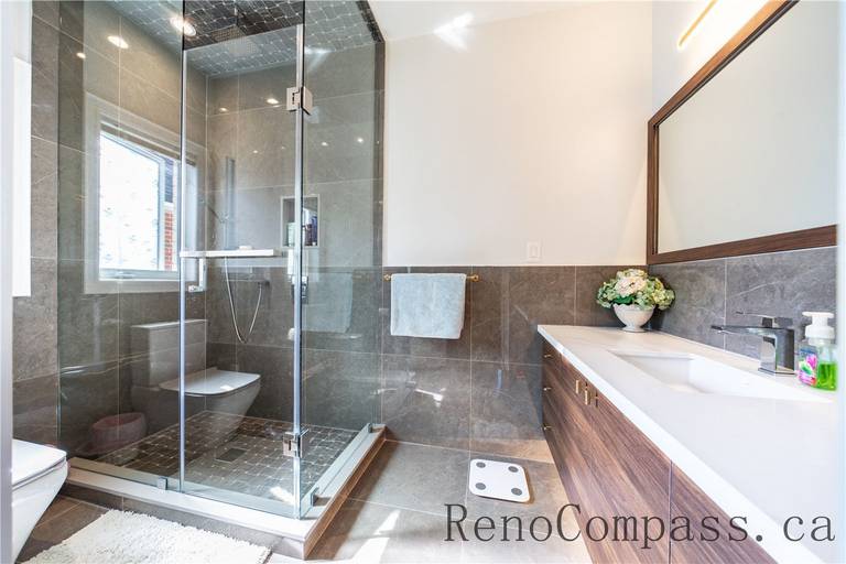This Richmond Hill bathroom renovation features a custom wood vanity, quartz countertop, LED mirror lighting, and a frameless glass shower with modern fixtures. The clean layout and premium finishes create a spa-like atmosphere while enhancing functionality, showcasing the craftsmanship of a trusted Toronto renovation company specializing in complete home interior renovations.