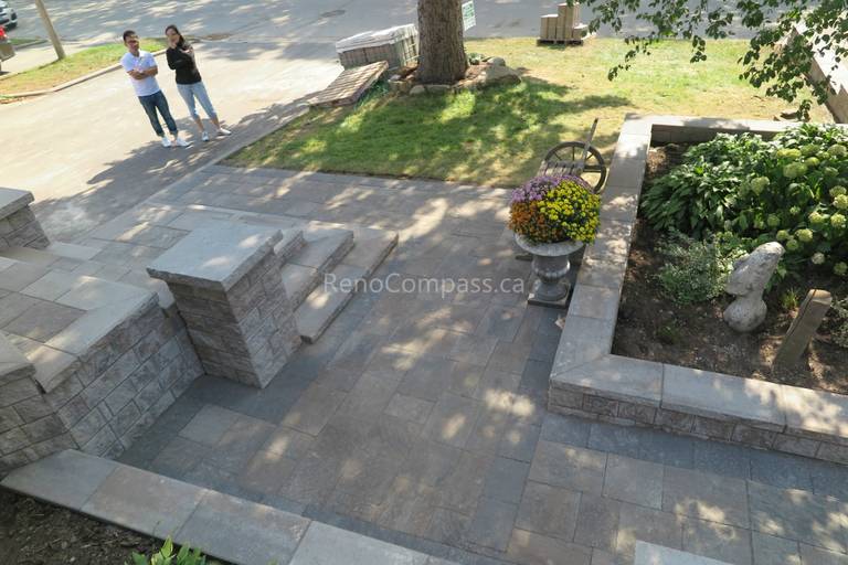 This Mississauga landscaping renovation showcases custom interlocking front entrance steps and landing patio designed for both visual impact and functionality. The multi-level stone layout creates a smooth transition from driveway to entrance while enhancing safety and flow. Premium interlocking pavers and stone columns add depth, structure, and a refined architectural feel to the exterior. Completed by Reno Compass Inc., this project highlights expert craftsmanship in residential interlocking and front yard landscaping design.