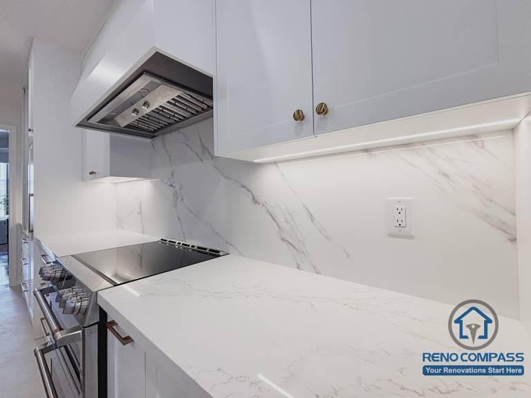 This Oakville kitchen renovation highlights the detailed execution of the cooking-side countertop, featuring a quartz surface with subtle veining and integrated under-cabinet lighting. Clean joints, precise alignment, and a continuous backsplash create a durable and easy-to-maintain workspace suited for daily cooking. The lighting enhances visibility while preserving a calm visual tone. Completed by Reno Compass, this kitchen detail reflects careful craftsmanship and a long-term approach to modern Oakville kitchen renovation.