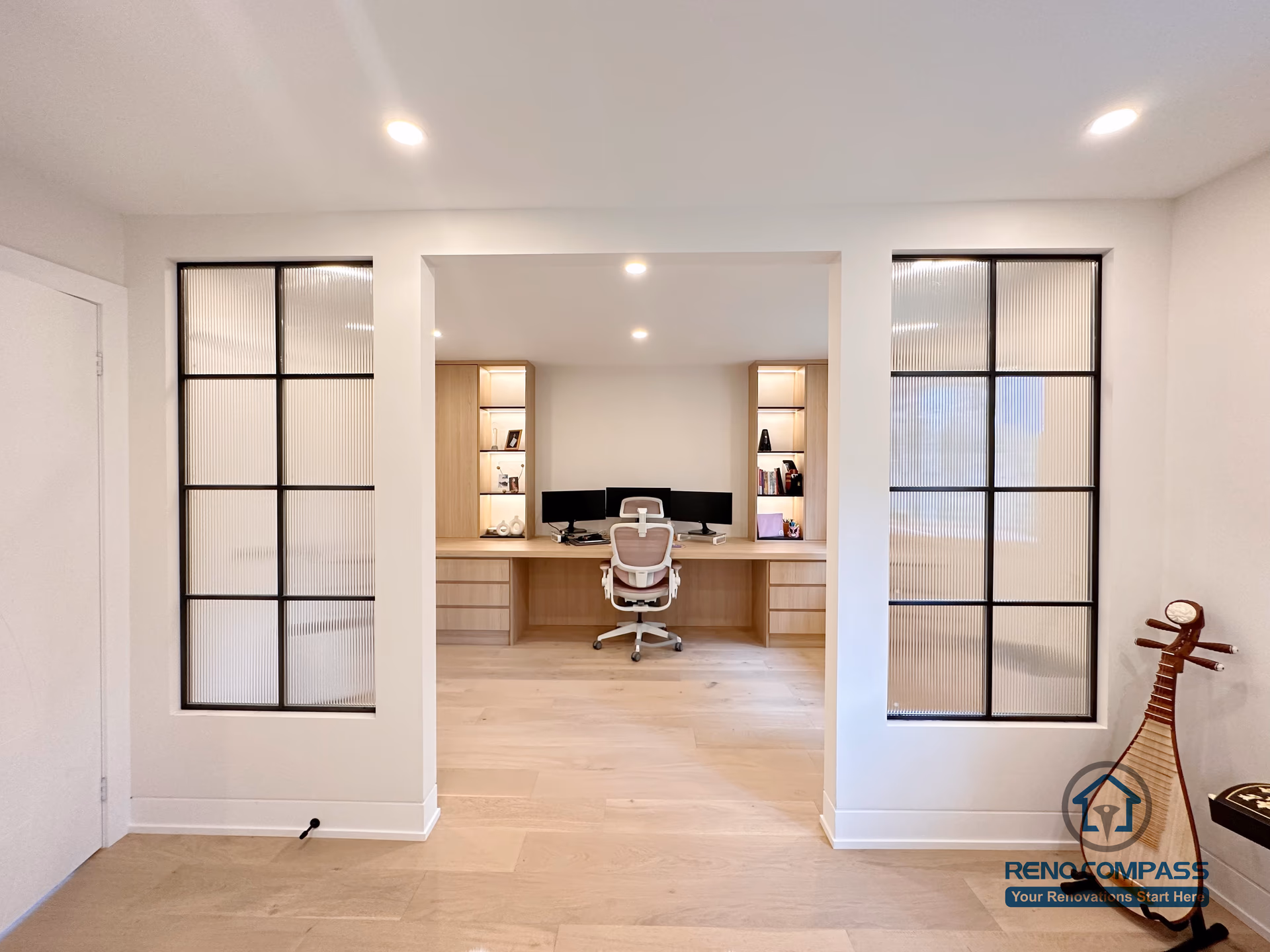 This Toronto home office renovation features light hardwood flooring, custom built-in desk cabinetry, and modern glass panel accents that create a bright and functional workspace. The open interior layout enhances natural light flow while maintaining visual separation, showcasing refined craftsmanship and flooring installation ideal for contemporary Toronto interior renovations.