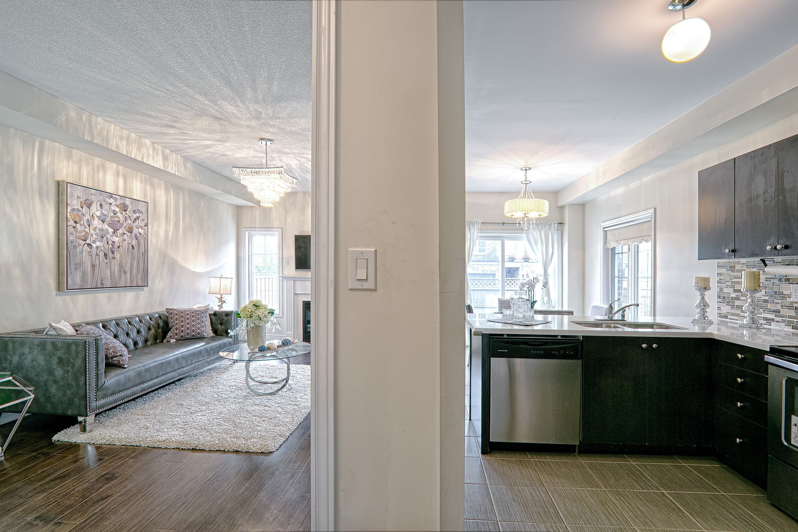 This open-concept interior highlights the seamless connection between the modern living room and upgraded kitchen space. Featuring dark hardwood flooring, contemporary cabinetry, quartz countertops, and elegant chandelier lighting, the layout enhances both visual flow and everyday functionality. The balanced mix of textures and neutral tones creates a cohesive and sophisticated home environment. Completed by a professional Toronto renovation company, this renovation showcases thoughtful space planning and modern interior design tailored for comfortable family living.