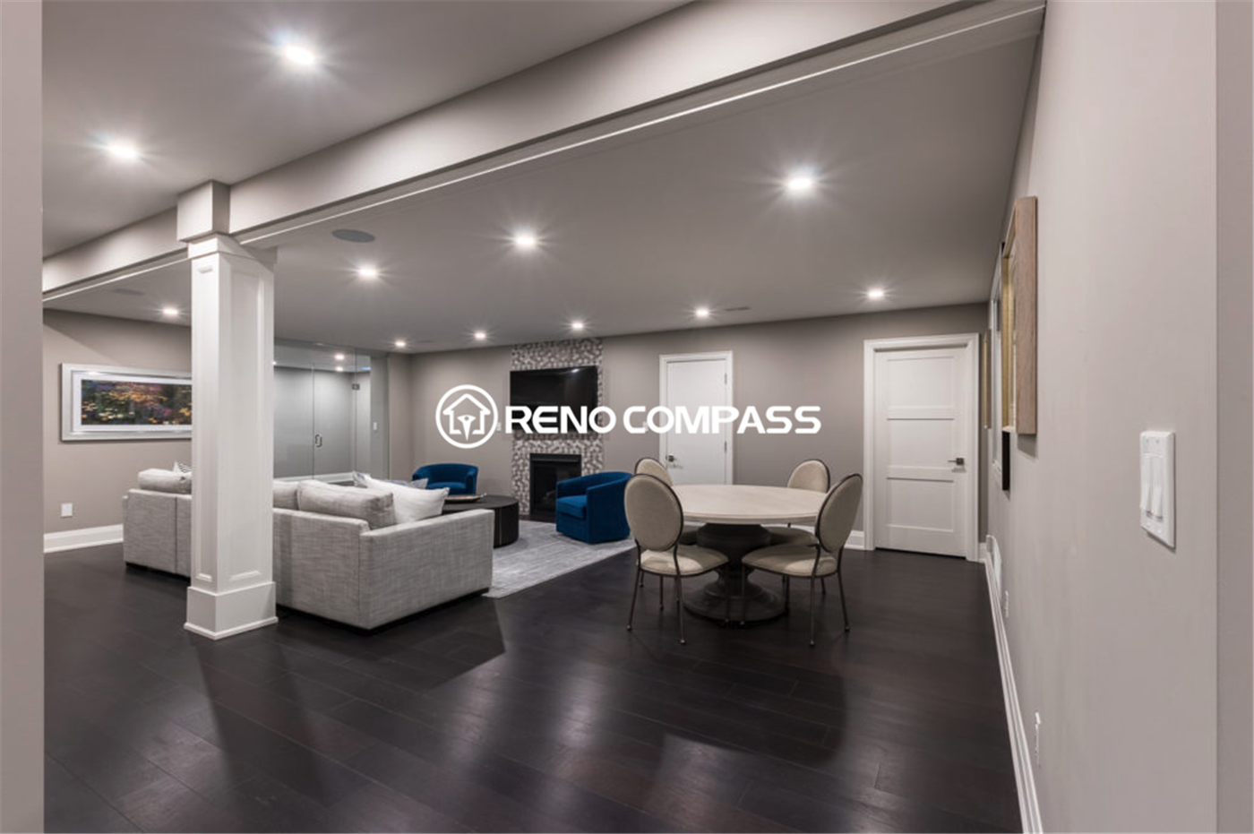 Spacious luxury basement renovation in Toronto featuring an open-concept layout with dark hardwood flooring, recessed ceiling lighting, modern lounge seating, and a stylish entertainment area. This elegant and functional basement living space was professionally designed and completed by a trusted Toronto renovation company, Reno Compass Inc.