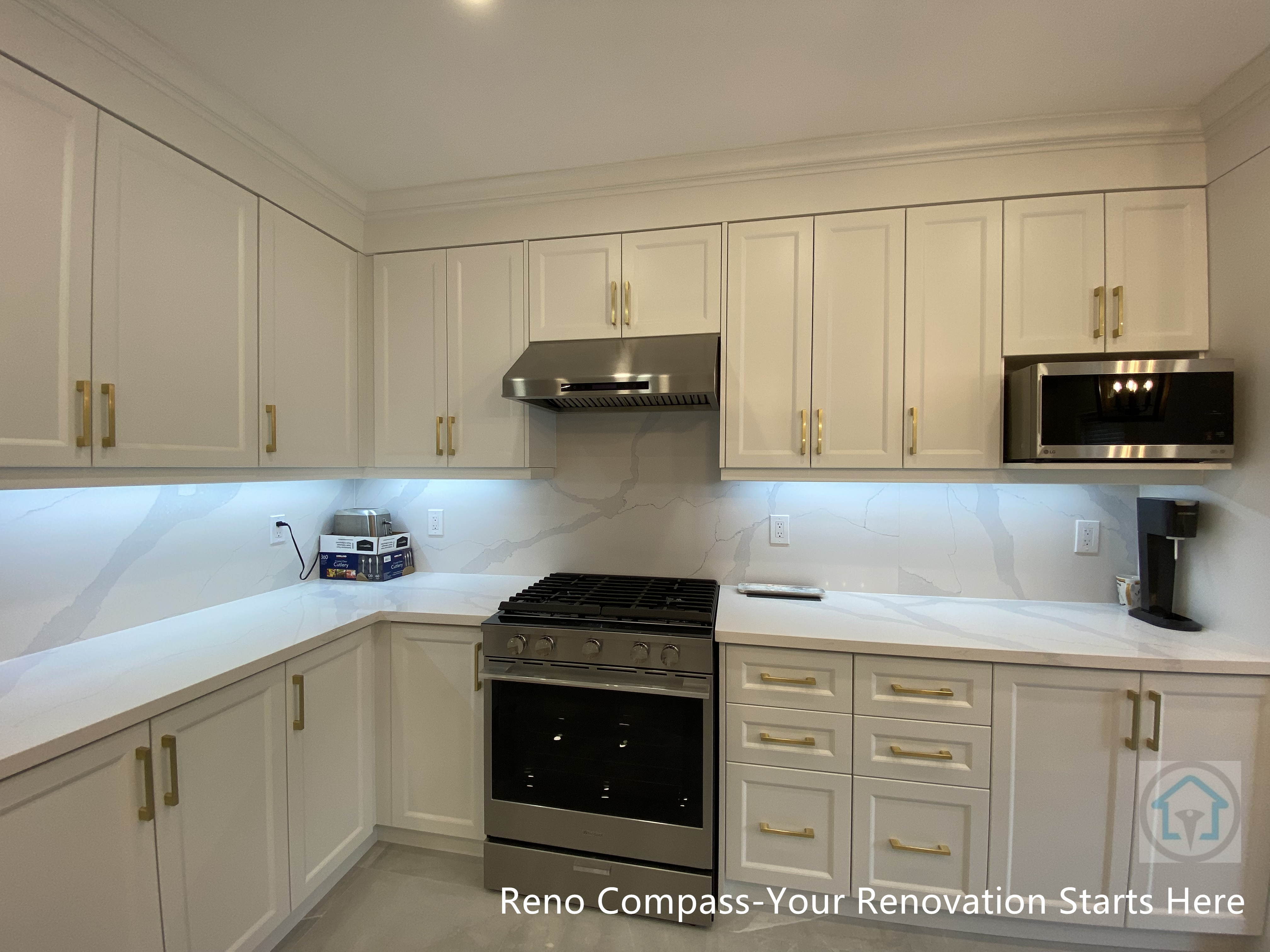 Modern kitchen renovation in Newmarket featuring custom white shaker-style cabinetry, quartz countertops, under-cabinet lighting, and stainless steel appliances. The U-shaped layout maximizes storage and efficiency while maintaining a clean, timeless aesthetic. Gold hardware accents add subtle warmth and detail, completed by a Toronto renovation company specializing in full interior home renovations.
