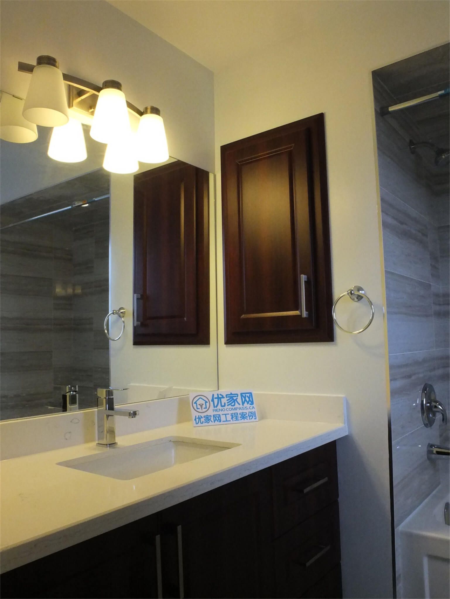 This photo showcases a finished bathroom as part of a North York interior renovation, featuring a modern vanity with integrated sink, dark wood cabinetry, quartz countertop, and a clean tub-shower combination with large-format wall tiles. The design balances functionality and durability, making it suitable for everyday family use while maintaining a timeless, contemporary look.