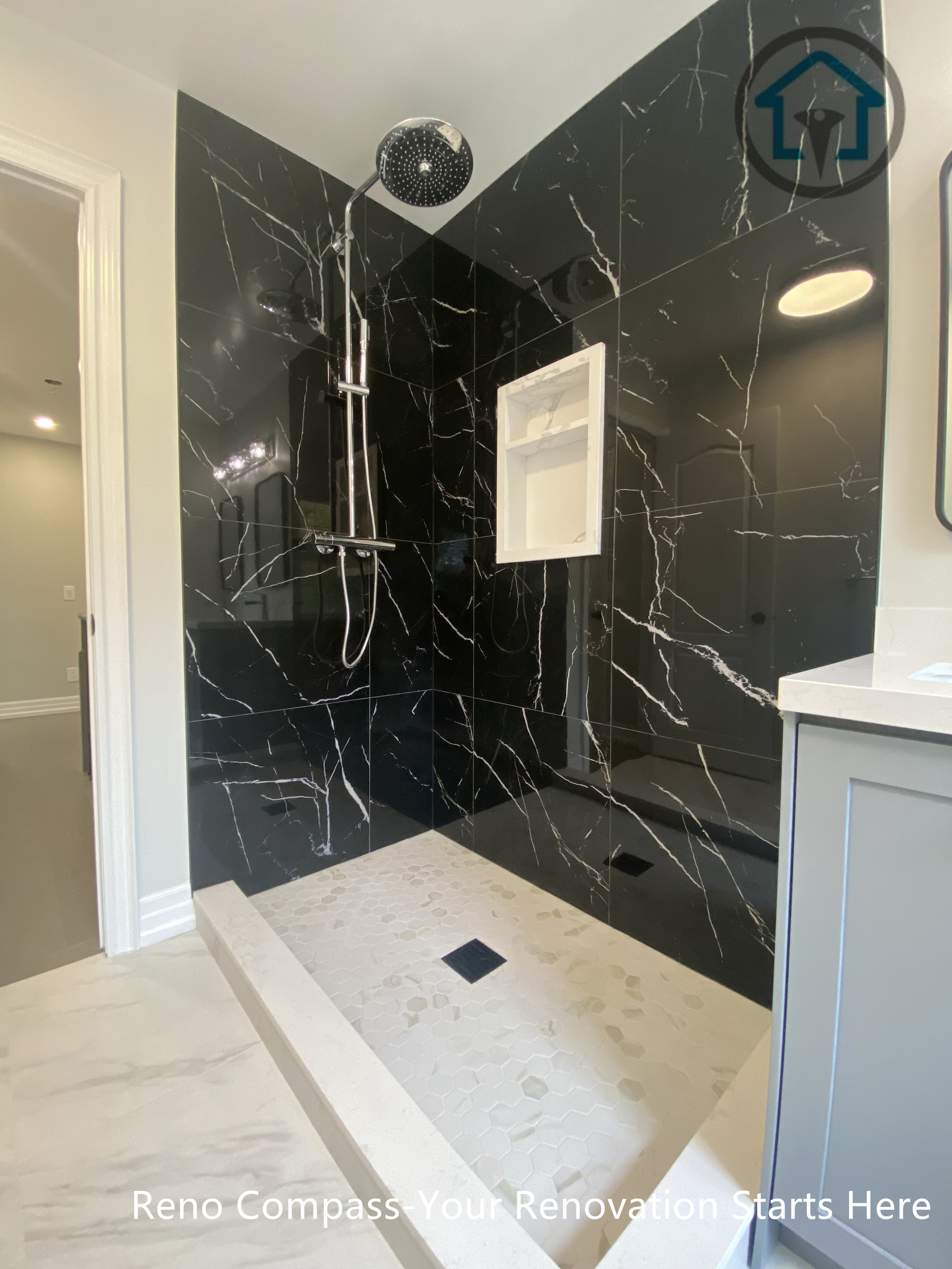 This walk-in shower showcases dramatic black marble–look porcelain tiles as a full-height feature wall. The rainfall shower system and integrated wall niche enhance both comfort and practicality, while the light shower base and floor tile create contrast and visual balance. The result is a bold yet refined shower design with a timeless, upscale feel.