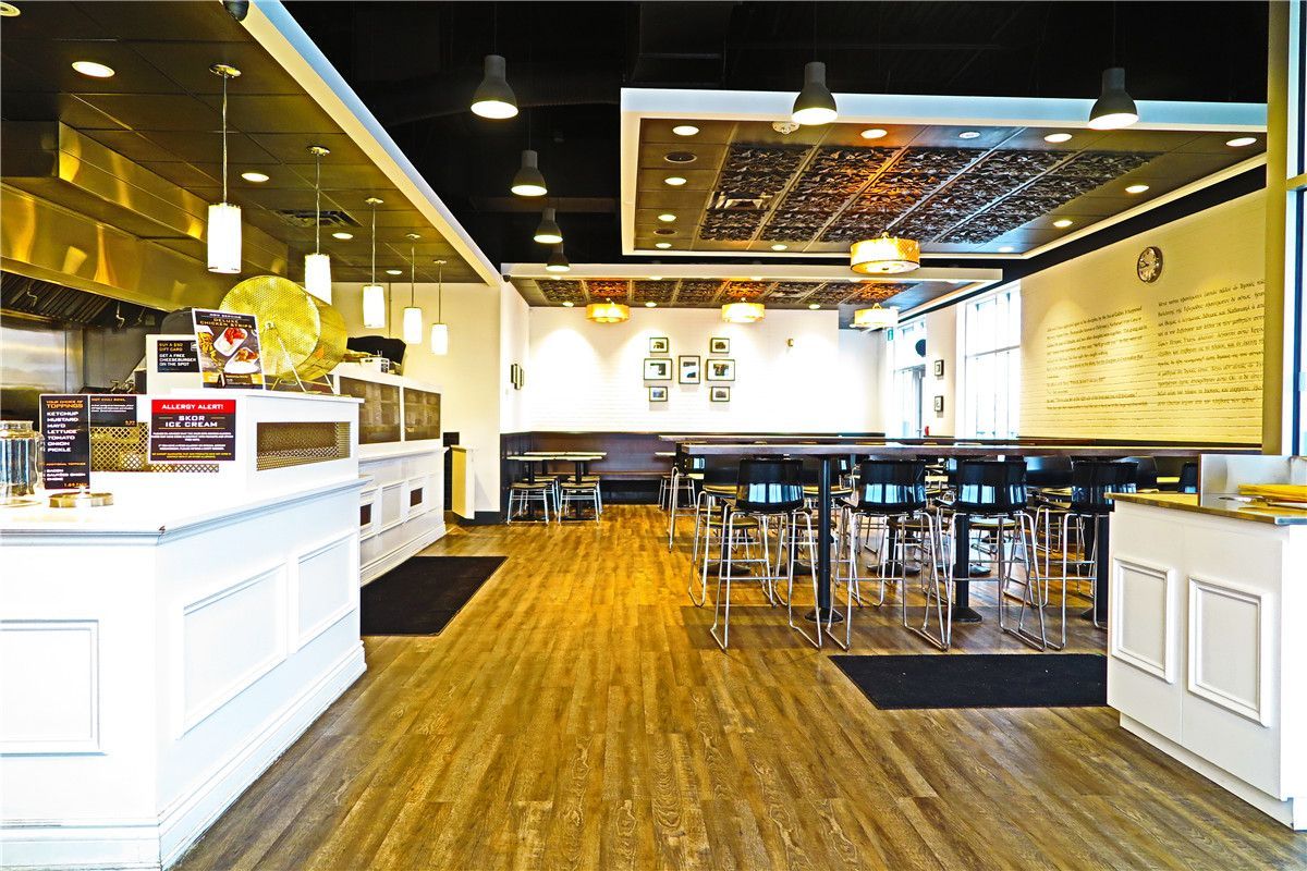 This completed Toronto restaurant renovation project showcases the finished dining area and full commercial interior upgrade by Reno Compass Inc. The space features modern wood-look commercial flooring, custom-built service counters, high-top seating arrangements, and integrated lighting systems designed to create a warm and inviting atmosphere.

The layout maximizes seating capacity while maintaining clear circulation pathways for both customers and staff. Decorative ceiling elements and wall-mounted design features enhance visual character while preserving a clean and professional commercial standard.

As a trusted Toronto renovation company, Reno Compass Inc. specializes in full restaurant interior renovations that improve operational efficiency, visual appeal, and long-term durability for food service businesses across the GTA.