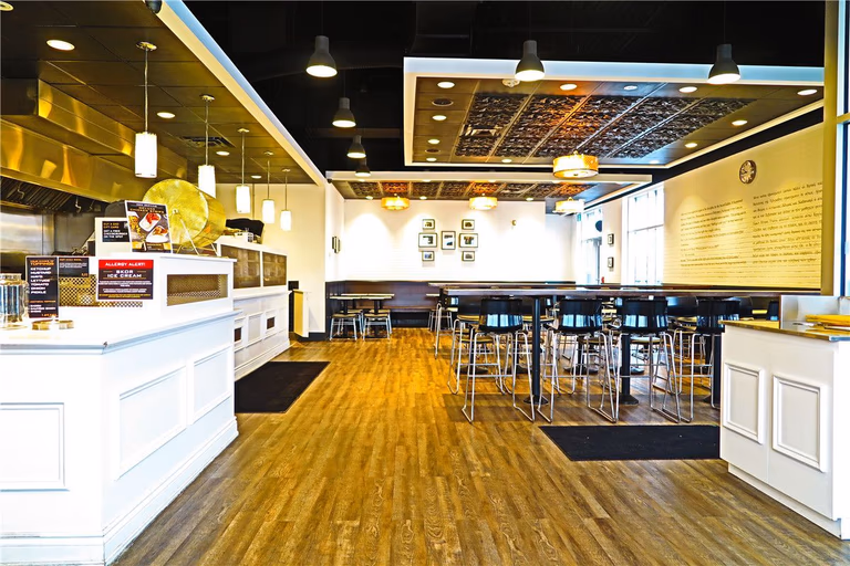 This completed Toronto restaurant renovation project showcases the finished dining area and full commercial interior upgrade by Reno Compass Inc. The space features modern wood-look commercial flooring, custom-built service counters, high-top seating arrangements, and integrated lighting systems designed to create a warm and inviting atmosphere.

The layout maximizes seating capacity while maintaining clear circulation pathways for both customers and staff. Decorative ceiling elements and wall-mounted design features enhance visual character while preserving a clean and professional commercial standard.

As a trusted Toronto renovation company, Reno Compass Inc. specializes in full restaurant interior renovations that improve operational efficiency, visual appeal, and long-term durability for food service businesses across the GTA.