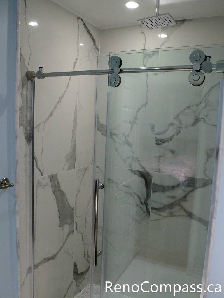 This Richmond Hill bathroom renovation features a sleek frameless glass shower enclosure, marble-look wall tiles, and a clean modern layout designed for comfort and durability. Completed by a professional Toronto renovation company, the space combines elegant finishes with practical functionality, creating a bright and contemporary bathroom upgrade for everyday living.