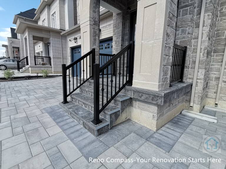 This Vaughan front entrance renovation highlights custom stone steps and a structured walkway leading to the main door. The natural stone finish, clean joint lines, and black metal railings create a refined and durable entry experience that seamlessly connects the driveway with the home’s front façade.