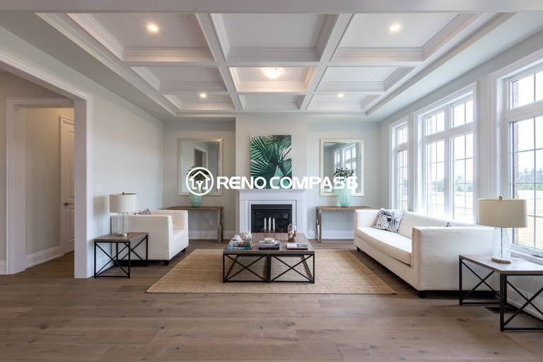 This Newmarket interior renovation features a bright and elegant living room with a coffered ceiling, large windows, engineered wood flooring, and a modern fireplace feature wall. The open layout and natural light create a comfortable and sophisticated living space. Completed by a trusted Toronto renovation company, Reno Compass Inc., the project highlights refined craftsmanship and timeless interior design.