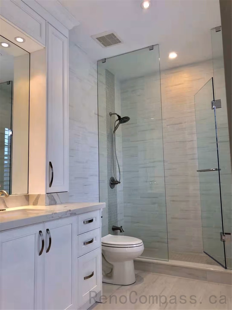 This North York bathroom renovation features a modern glass shower enclosure with marble-look wall tiles, a custom vanity with quartz countertop, and coordinated brushed metal fixtures. The bright layout enhances space, functionality, and everyday comfort while maintaining a clean contemporary style. Completed by a professional Toronto renovation company focused on quality craftsmanship and refined bathroom design.