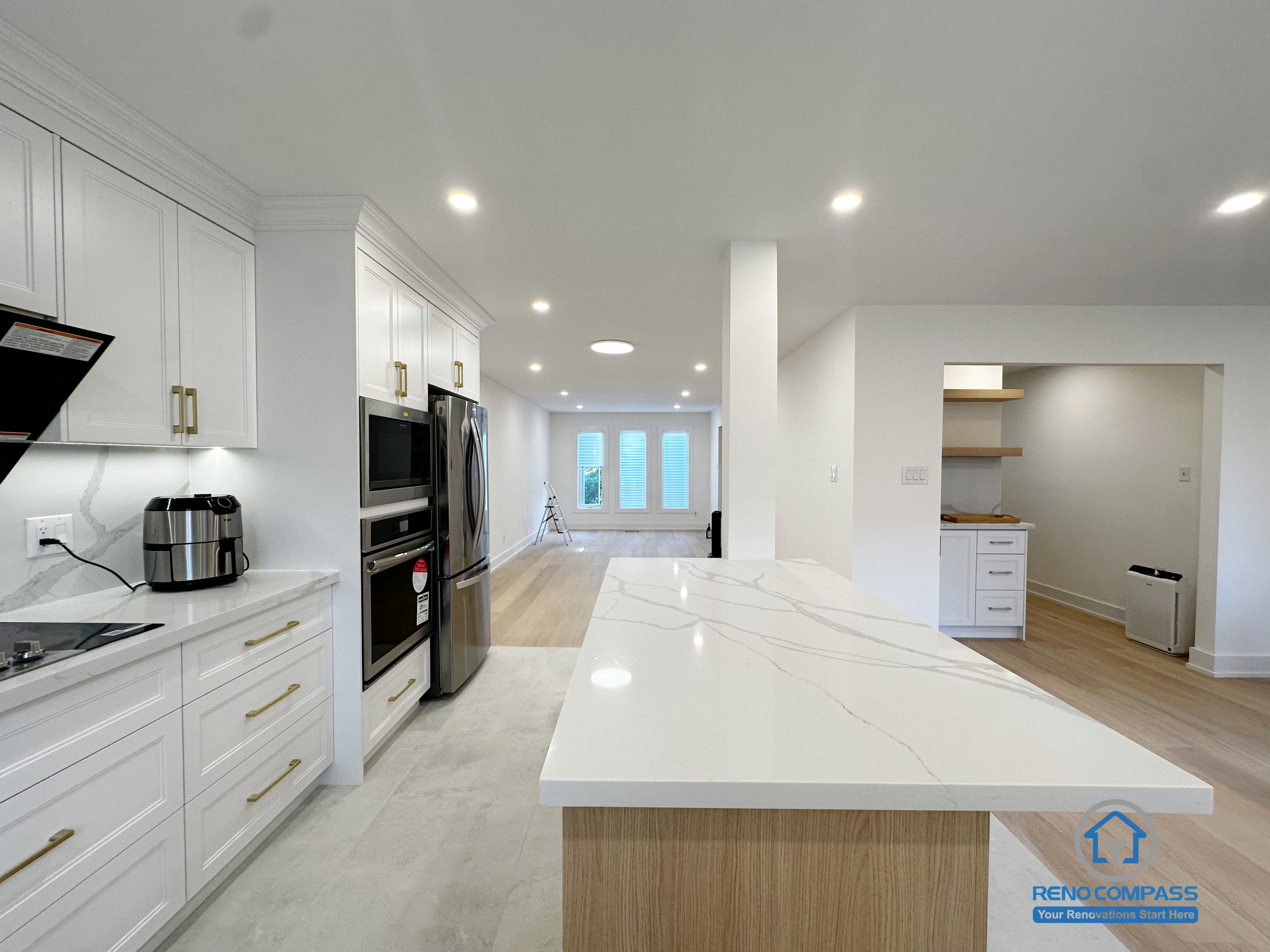 This Richmond Hill interior renovation highlights a quartz island kitchen viewed along an extended sightline toward the living area. The seamless countertop surface, integrated appliances, and recessed lighting create a clean and cohesive visual experience. The long-axis perspective emphasizes openness and spatial continuity, making the kitchen feel connected yet well-defined within the overall layout. Completed as part of a Toronto renovation project focused on material quality, visual flow, and practical everyday use.